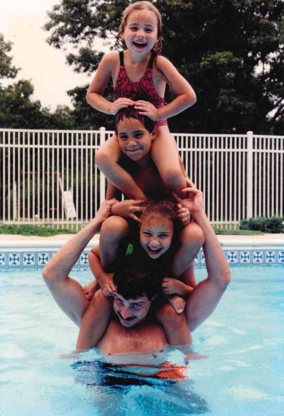 The Homerick kids stacked on their dad's shoulders in a pool, from the family album