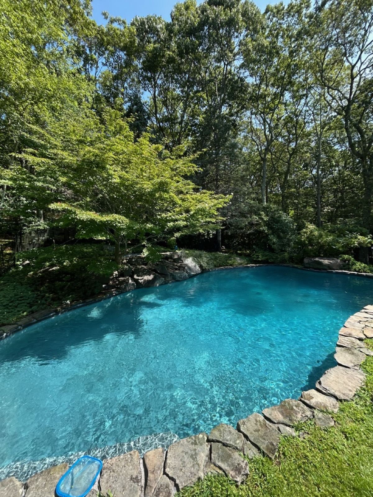 An inground pool with stonework and a water feature